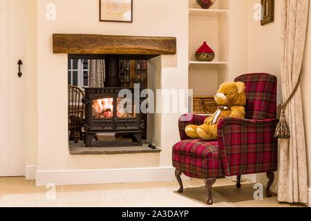 Gemütlichen Kamin mit Holzofen und teddy Bären in einem Wohnzimmer Home Interior, Großbritannien Stockfoto