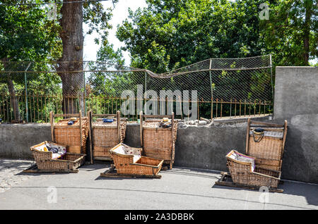 Weidenkorb Schlitten in Monte, Madeira, Portugal. Traditionelle Transportmittel zwischen Monte und Funchal, jetzt Touristenattraktion. Typische Strohhüte Der Carreiros Treiber, mit Vorzeichen Madeira. Stockfoto