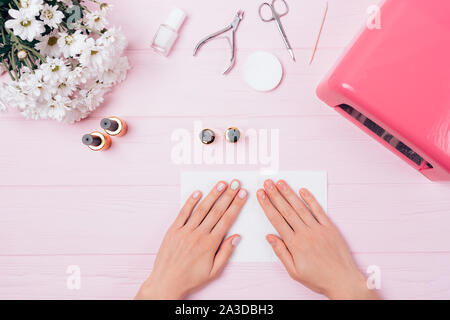 Blick von oben auf die weibliche Hände mit Maniküre auf einem rosa Tabelle Stockfoto