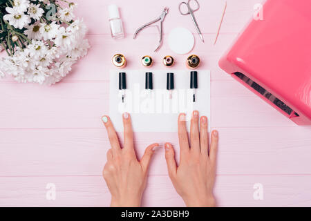 Weibliche Hände mit Maniküre auf einem rosa Tabelle, Ansicht von oben Stockfoto