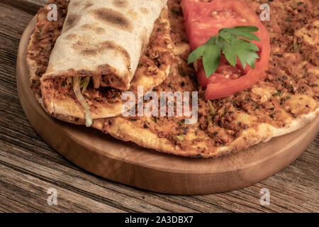 Traditionelle türkische Pizza, die Rinderhackfleisch und Zwiebeln auf einem hölzernen Tisch gemacht wird Stockfoto
