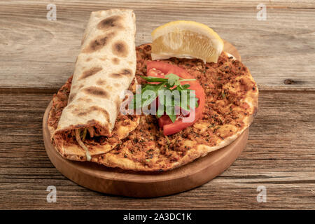 Traditionelle türkische Pizza, die Rinderhackfleisch und Zwiebeln auf einem hölzernen Tisch gemacht wird Stockfoto