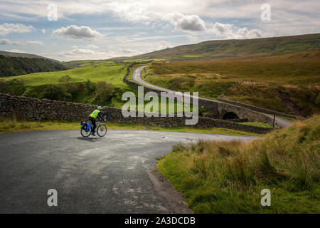 Radtour: Langstrecken-Radtour mit großen Fahrradtaschen auf der Tan Hill Road in Richtung Reeth durch Archengarthdale, Yorkshire Dales National Park Stockfoto