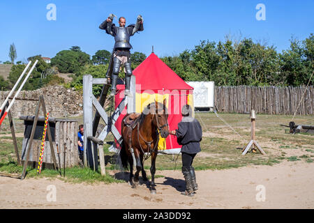 Mittelalterliche Ritter in Rüstung mit Holz- Hebel angehoben sein Pferd vor dem Fischerstechen im Château de Tiffauges, Vendée, Frankreich Stockfoto