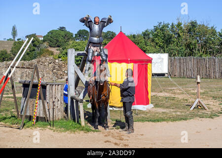 Mittelalterliche Ritter in Rüstung mit Holz- Hebel angehoben sein Pferd vor dem Fischerstechen im Château de Tiffauges, Vendée, Frankreich Stockfoto