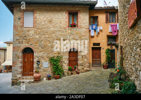 Mittelalterliche gepflasterte Gasse und alte Häuser aus Stein mit hängenden Bettwäsche in Italien Stockfoto