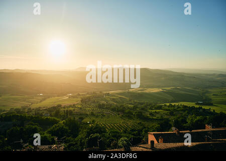 Luftaufnahme von landschaftlich reizvollen Hügel Landschaft mit grünen Wäldern Feldern Gebäude und die Sonne in der Region Toskana in Italien Stockfoto