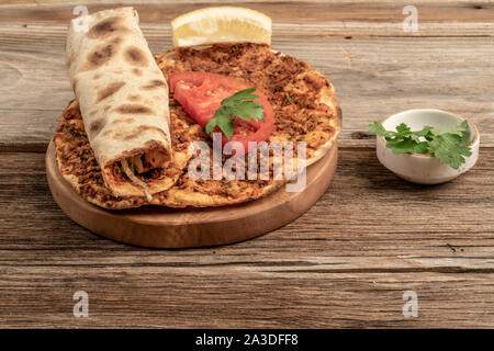 Traditionelle türkische Pizza, die Rinderhackfleisch und Zwiebeln auf einem hölzernen Tisch gemacht wird Stockfoto