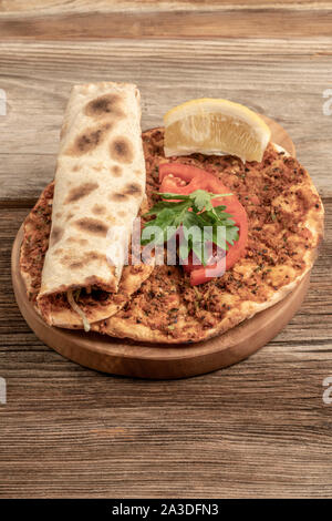 Traditionelle türkische Pizza, die Rinderhackfleisch und Zwiebeln auf einem hölzernen Tisch gemacht wird Stockfoto