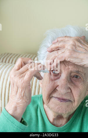 Eine ältere Frau Augentropfen, die in ihren Augen von sich selbst Stockfoto