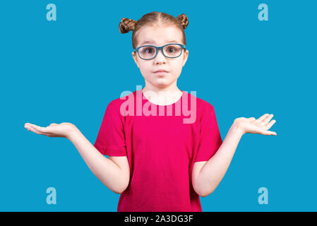 Kleines Mädchen mit Brille nicht weiß und breitet ihre Arme zu den Seiten. Auf einem blauen Hintergrund. Stockfoto