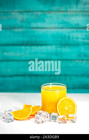 Glas Orangensaft und Orangen auf einem weißen Tisch und die Holzwand mit Platz für Grafiken und Text Stockfoto