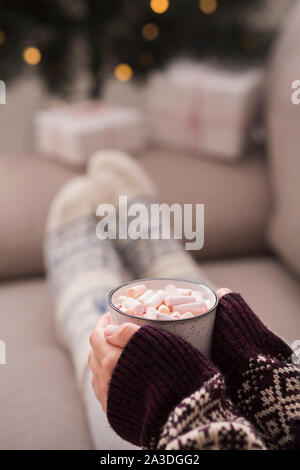 Frau in Weihnachten Socken und Pullover mit Muster trinken Kakao Stockfoto