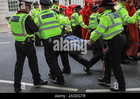 London, UK, 07. Okt 2019. Polizisten halten Sie, dann mitnehmen Auslöschung Rebellion Demonstrant. Weitere Verhaftungen sind von der Polizei in Millbank, und in der Nähe von Lambeth Bridge, Westminster heute Abend. Stockfoto