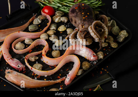 Gesunde Ernährung Konzept. Mediterrane Diät essen. Octopus, Aal Fisch und Muscheln auf dunklem Hintergrund. Meeresfrüchte Konzept Stockfoto