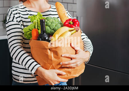 Frau, die in ihrer Küche und hält eine Tüte voller Produkte Stockfoto