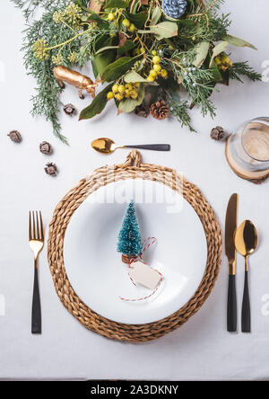 Elegante Weihnachten mit gold und weiß Dekoration und golden Besteck. Pine Tree Figurine auf dem Teller von oben Stockfoto