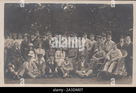 Jahrgang des frühen 20. Jahrhunderts photographische Postkarte zeigt eine Gruppe von Verletzten und Kranken WW1 Soldaten der britischen Armee. Einer der Soldaten ist in einem Rollstuhl. Stockfoto