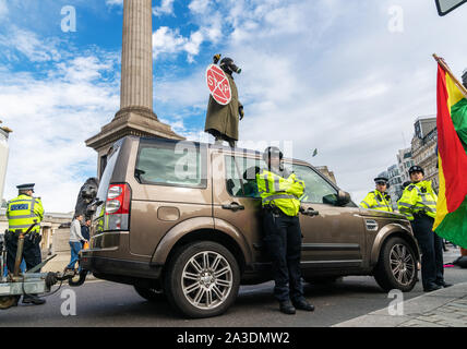 7 Oct 2019 - London, UK. Eine Demonstrantin trägt eine Gasmaske auf ein Auto Sperrung der Straße auf dem Trafalgar Square. Stockfoto