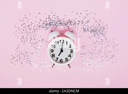 Weiß Wecker auf der rosa Hintergrund mit sternförmigen Konfetti Stockfoto