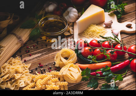 Lecker schmackhafte italienische Spaghetti pasta Zutaten für Küche Küche mit Tomate, Käse Parmesan, Olivenöl, Fettuccine und Basilikum auf Holz braun Stockfoto