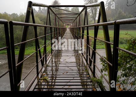 Stahlbrücke mit hölzernen walkpath. Fluß bei schlechtem Wetter. Stockfoto