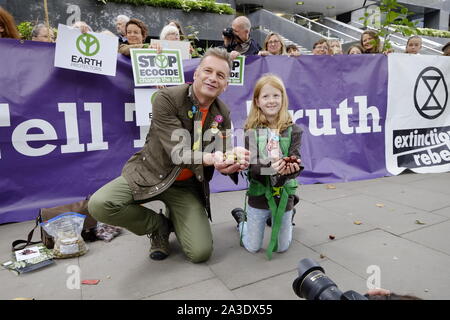 Naturforscher und TV-Moderator Chris Packham leitet ein Demo außerhalb des HQ von Network Rail, Euston, die Zerstörung der alten Wälder entlang der neuen vorgeschlagenen HS2 Bahnverbindung zwischen London, Birmingham, Manchester und Leeds zu verhindern. Dazu gehören Süden Cubbington Holz in Warwickshire, die gut ist seine Bluebells, die biologische Vielfalt und die Öffentlichkeit Wissen geht. Die Fahne hinter ihm sagt, "die Wahrheit" einer der vom Aussterben Rebellion Forderungen erklären. Ein Demonstrant hält einen Aushang der Umweltzerstörung". Chris Packham auch sprechen für TV. Ein junger Demonstrant verband ihn in Teilen eine Handvoll Eicheln. Stockfoto