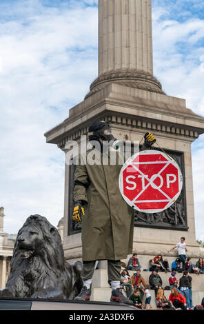 7 Oct 2019 - London, UK. Eine Demonstrantin trägt eine Gasmaske auf ein Auto Sperrung der Straße auf dem Trafalgar Square. Stockfoto