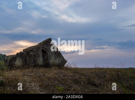 Alte Stein in Form der menschlichen Kopf im Feld auf dem Hintergrund des blauen Himmels Stockfoto