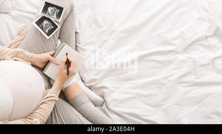 Schwangere Frau schreiben Gedanken im Notebook für Speicher Stockfoto