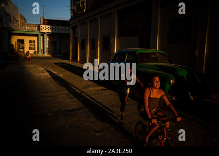 Kinder fahren Fahrräder in den Straßen von Havanna während des Sonnenuntergangs. Stockfoto