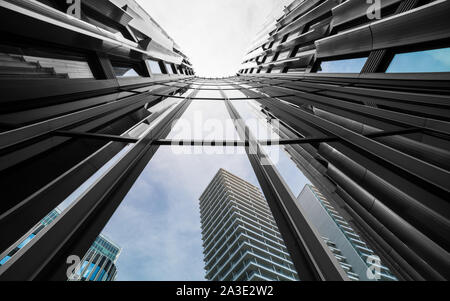 Modernes hohes Gebäude Detail der Fassade von unten. Spiegelung von konkreten Wolkenkratzer, blauer Himmel, glänzend Glas Fenster. Künstlerische architektonischen Hintergrund. Stockfoto