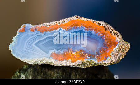 Poliert Achat Querschnitt. Schönen welligen Muster auf glatte Schnittfläche. Blaue Perle detail. Ungleichmäßige rusty Grenze, Spiegelungen auf glänzenden dunklen Hintergrund. Stockfoto