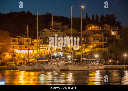 Nächtliche Abend lowlight Szene rund um den Hafen und das Meer in der Griechischen Ferienort Kassiopi auf der Insel Korfu in Griechenland mit Booten Stockfoto