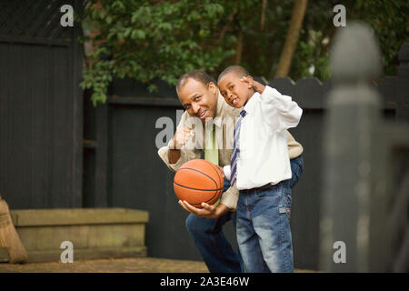 Porträt eines erwachsenen Mann hält einen Basketball mit seinem jungen Sohn. Stockfoto