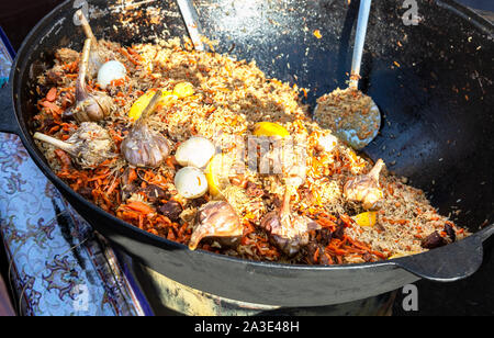 Appetitlich traditioneller Usbekischer Pilaw mit Gemüse in einem großen Kessel im Freien Stockfoto