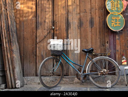 Blue Bicycle auf geschlossenen Holztür der Chinesischen alter Markt Gasse, Sanhe, Anhui, China schiefen Verrostet Stockfoto