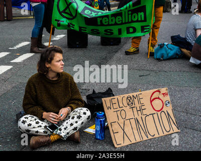 London, Großbritannien. 7. Oktober 2019. Eine Demonstrantin sitzt in Breiten Heiligtum mit einem Plakat "Willkommen in der 6. Vom Aussterben bedroht'. Aussterben Rebellion der Internationalen Rebellion von Besatzungstruppen elf Standorten in Ministerien beginnen, Downing Street, The Mall, Westminster und Lambeth Brücken, den Verkehr zum Erliegen bringen. Sie fordern die Regierung auf, die Wahrheit über das Klima und ökologische Not sagen, Akte der Verlust der biologischen Vielfalt Einhalt zu gebieten, verringerte Emissionen in Net Zero und erstellen und von einem Bürger Baugruppe geführt werden. Peter Marshall / alamy Leben Nachrichten Stockfoto