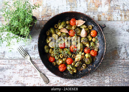 Gebackener Rosenkohl in einer Pfanne mit Tomaten, Knoblauch und Oliven. Veganes essen. Diät Konzept. Herbst essen. Stockfoto