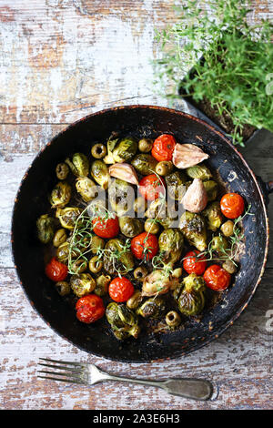 Gebackener Rosenkohl in einer Pfanne mit Tomaten, Knoblauch und Oliven. Veganes essen. Diät Konzept. Herbst essen. Stockfoto