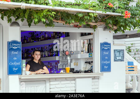 Mädchen Cocktailbar Kellner mit Blick auf eine kleine Bar im griechischen Ferienort Kassiopi auf der griechischen Insel Korfu Stockfoto