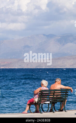 Mann und Frau sitzen Rücken an Rücken und schauen in entgegengesetzte Richtungen auf einer Bank am Meer, sprechen nicht Stockfoto