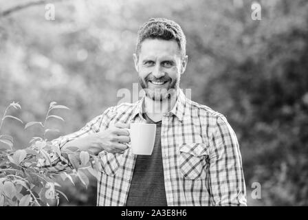 Erfrischendes Getränk. Man bärtige Kaffee Bauer halten Becher Natur Hintergrund. Grüner Tee Plantage. Vollständige blatt Tee. Hervorragender Geschmack. Genießen Sie heiße Getränke. Natürliche trinken. Gesunde Lebensweise. Ich bevorzuge grünen Tee. Stockfoto