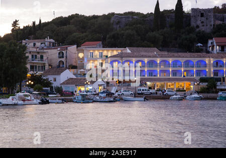 Nächtliche Abend lowlight Szene rund um den Hafen und das Meer in der Griechischen Ferienort Kassiopi auf der Insel Korfu in Griechenland mit Booten Stockfoto