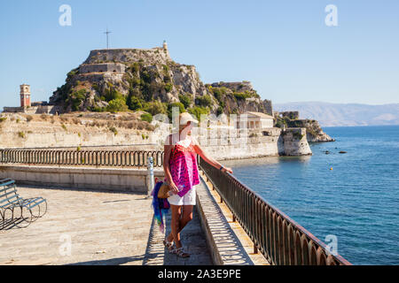 Frau auf der Hafenseite mit den alten venezianischen Festung auf der griechischen Insel Korfu in Griechenland Stockfoto