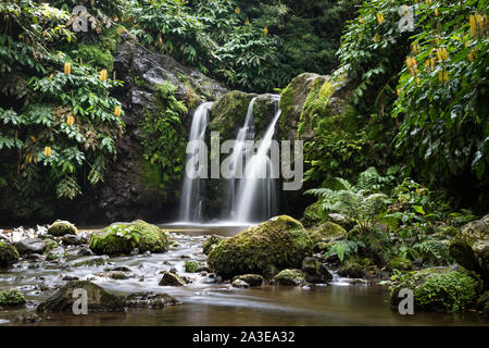 Natürlicher Wasserfall von Felsen und Laub im Parque Natural da Ribeira dos Caldeirões, São Miguel, Azoren umgeben. Lange Belichtung Bild. Stockfoto