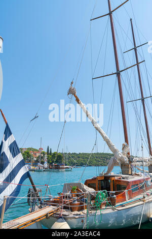 Classic Old Yacht mit lackierten Holz- Kabine und Spieren mit Seilen und bleibt nah Aufund grüne low Hügel im Hintergrund von Ermioni Hafen. Stockfoto