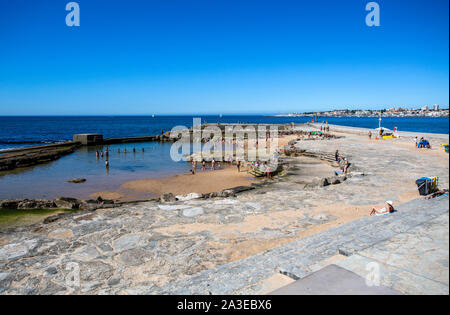 Menschen die Sonne genießen und den Atlantischen Ozean um einen geschützten Pool auf der auf den Felsen der Strand von Tamariz, in Estoril, Portugal gebaut Stockfoto