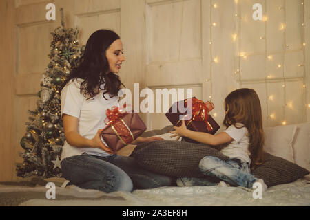 Familie feiert Weihnachten. Gemütliche Weihnachten Morgen. Mutter und Tochter geben einander Weihnachtsgeschenke. Geschenkboxen. Frohe Weihnachten und guten Rutsch holida Stockfoto