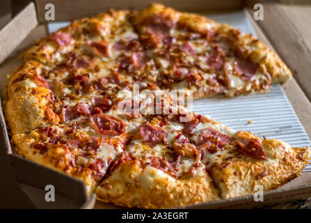 Ein Herausnehmen des Fleisches geliebte Pizza noch in der Box, mit einem Stück fehlt Stockfoto